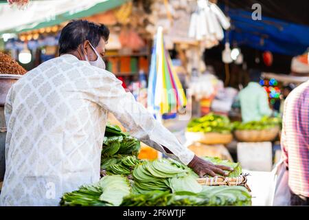 K.R.Market, Bangalore, Indien - Februar 06,2021: Betel verlässt den Verkäufer, der die Blätter in seinem Laden arrangiert Stockfoto