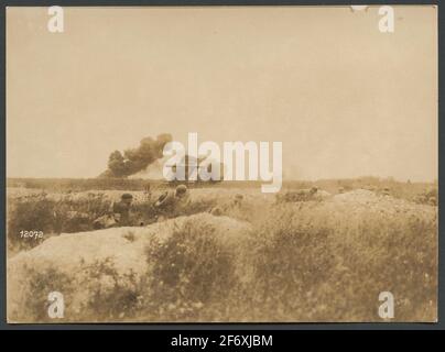 Das Bild zeigt Soldaten, die in einem Graben Schutz nehmen und beobachten, wie sich ein Panzer auf dem Schlachtfeld bewegt.Es gibt mehrere Explosionen von Artillerie .. Das Bild zeigt Soldaten, die bei einer Schießerei Schutz ergreifen und einen Panzer beobachten, der sich auf dem Schlachtfeld bewegt.Es gibt mehrere Explosionen durch Artillerie. Stockfoto