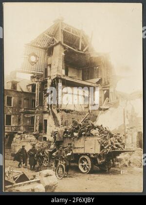 Das Bild zeigt Soldaten, die sich auf einer Straße vor einer Ruine in einer geklebten Stadt bewegen.im Vordergrund geht eine Gruppe zu Fuß.EINE Person führt ein Fahrrad, Neben ihm geht ein verwundete einen verputzten Arm, hinter dem sie einen Lastwagen fahren, der zu Kriegsmaterial transportiert wird und Soldaten auf der Flocke sitzen. Das Bild zeigt Soldaten, die sich auf einer Straße vor einer Ruine in einer zerbrochenen Stadt bewegen.im Vordergrund geht eine Gruppe zu Fuß.EINE Person führt ein Fahrrad, Neben ihm geht ein verwundete einen verputzten Arm, hinter dem sie einen Lastwagen fahren, der zu Kriegsmaterial transportiert wird und Soldaten auf der Flocke sitzen. Stockfoto