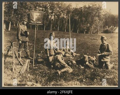 Das Bild zeigt eine Gruppe von Soldaten, die sich auf einer Liegewiese befinden, wo sie eine Handystation eingerichtet haben.das Schild "Fernspricher" verweist auf ein Telefon.einer der Männer sitzt auf dem Bauch und redet im Kopfhörer, während er schreibt.auf der linken Hand, Sie sehen eine Kabeltrommel und drei Gewehre .. Das Bild zeigt eine Gruppe von Soldaten, die sich auf einer Liegewiese befinden, wo sie eine Handystation eingerichtet haben.das Schild "Fernspricher" bezieht sich auf ein Telefon.einer der Männer sitzt auf dem Bauch und redet beim Schreiben im Kopfhörer.auf der linken Seite sehen Sie eine Kabeltrommel und drei Gewehre. Stockfoto