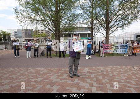 Ein Protestler mit Maske hält während der Demonstration eine Rede, während er ein Plakat hält.Wir brauchen keine Waffen, sondern Corona Gegenmaßnahmen." Senioren zeigen ihre Meinung zu verschiedenen innenpolitischen Themen. Sie fordern unter anderem die Absage der Olympischen Spiele 2020 in Tokio, da sie die Verbreitung des Corona-Virus in Japan befürchtet. Stockfoto