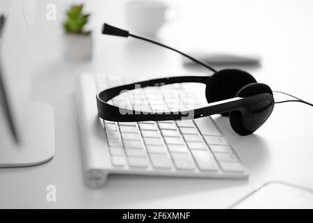 Das Headset liegt auf der Computertastatur auf dem Tisch Im Büro oder zu Hause - das Konzept von Ein Callcenter und Kundensupport oder der Verkauf von Ser Stockfoto