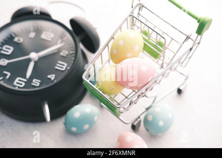 osterkonzept mit Ei im Warenkorb und Uhr auf Hintergrund. Stockfoto