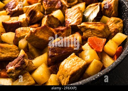 Fleischeintopf mit Kartoffel aus nächster Nähe. Hausgemachte Schweinefleisch warme Mahlzeit in Gusseisenpfanne. Stockfoto