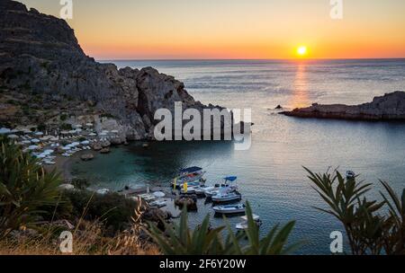 Saint Paul's Bay Strand mit Booten in Lindos, Rhodos, Griechenland, wunderschöne Meereslandschaft mit aufgehender Sonne Stockfoto