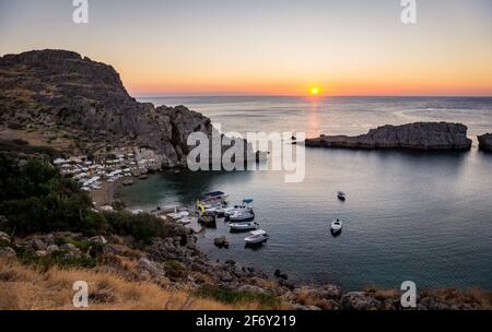 Saint Paul's Bay Strand mit Booten in Lindos bei schönem Sonnenaufgang, Rhodos, Griechenland Stockfoto