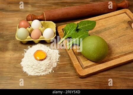 Grünes Teigbrötchen für die Herstellung von Nudeln, zubereitet auf dem Tisch mit Zutaten, traditionelle italienische Küche Stockfoto