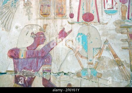 altägyptisch bemalte hieroglyphe Schnitzerei des Pharoah Seti mit dem gott der Regeneration Osiris. Mauer am Tempel zu Oiris bei Abydos, Ägypten. Stockfoto