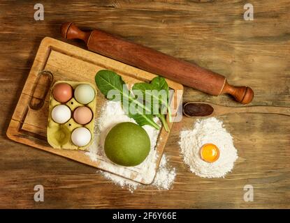 Grünes Teigbrötchen für die Herstellung von Nudeln, zubereitet auf dem Tisch mit Zutaten, traditionelle italienische Küche Stockfoto