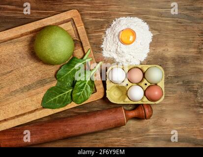 Grünes Teigbrötchen für die Herstellung von Nudeln, zubereitet auf dem Tisch mit Zutaten, traditionelle italienische Küche Stockfoto