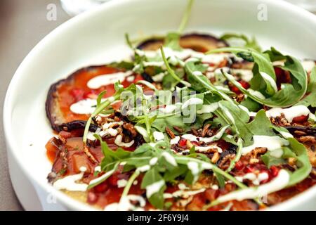 Auberginen-Carpacio in Tomatensauce mit Rucola, Granatapfelkernen und Walnüssen mit weißem Dressing Stockfoto