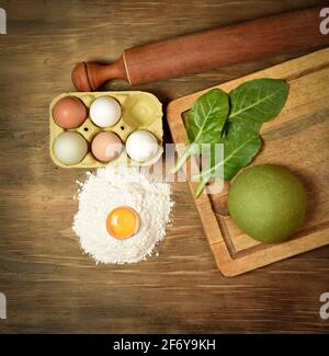 Grünes Teigbrötchen für die Herstellung von Nudeln, zubereitet auf dem Tisch mit Zutaten, traditionelle italienische Küche Stockfoto