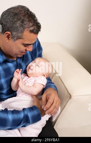 Großvater hält eine zwei Monate alte Enkelin, verstört, weinend Stockfoto