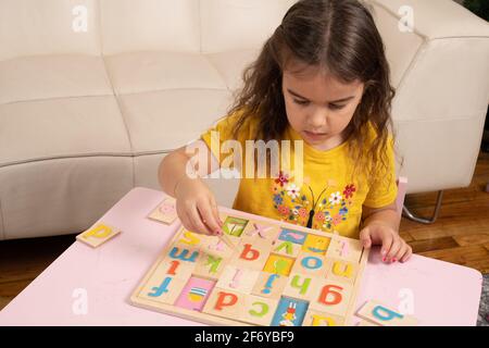 Vier Jahre altes Mädchen spielen mit bunten Holz Alphabet Puzzle Stockfoto