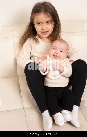 Vier Jahre altes Mädchen posiert mit zwei Monate altem Baby Schwester Stockfoto