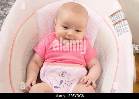 Nahaufnahme eines zwei Monate alten Mädchens, auf dem Kindersitz, lächelnd Stockfoto