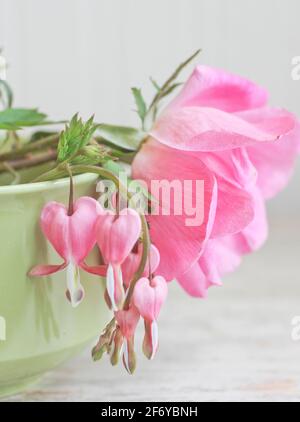 Wilde rosa Rose mit blutenden Herzen Blumen in Vintage-Tee stillleben im cup Stockfoto