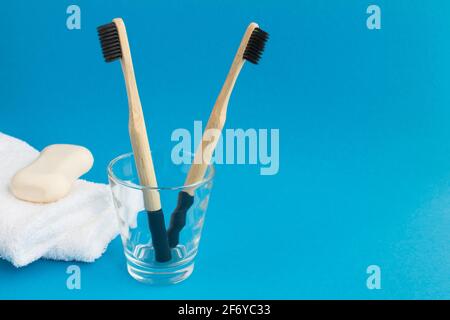 Nahaufnahme auf Bambuszahnbürsten auf dem Glas, weiße Handtücher und Seife auf dem blauen Hintergrund Stockfoto