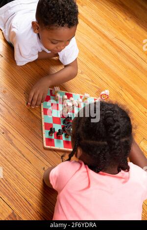 Das 11-jährige Mädchen spielt mit ihrem 6-jährigen Bruder Schach, spielt Spiel und lehrt ihn, wie man spielt Stockfoto