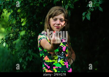 Defokussiert Mädchen in hellen Kleidern zeigt verschwommene Erdbeeren auf einem verschwommenen dunkelgrünen Natur Hintergrund. Feld, Wald. Harmonie mit der Natur. Nicht fokussiert Stockfoto