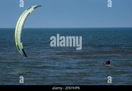 03. April 2021, Schleswig-Holstein, Westerland/Sylt: Ein Kitesurfer fährt bei strahlendem Sonnenschein am Strand von Westerland entlang. Foto: Axel Heimken/dpa Stockfoto