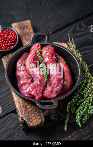 Rohes Filetfilet aus Hammelfilet, Lammfilet in rustikaler Pfanne mit Thymian. Schwarzer Holzhintergrund. Draufsicht Stockfoto