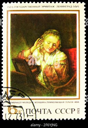 MOSKAU, RUSSLAND - 11. JANUAR 2021: Die in der UdSSR (Russland) gedruckte Briefmarke zeigt junge Frau beim Versuch an Ohrringen, Rembrandt (1654), ausländische Gemälde in Stockfoto