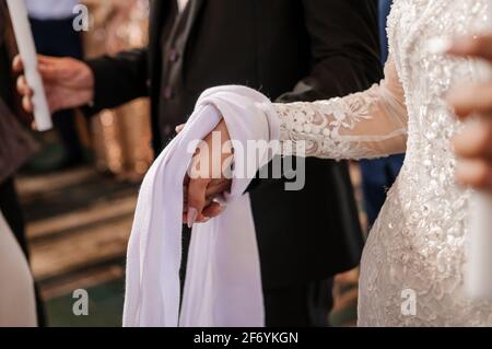 Die Hände der Braut und des Bräutigams sind mit einem bestickten Handtuch gebunden. Ukrainische Hochzeitstraditionen Stockfoto