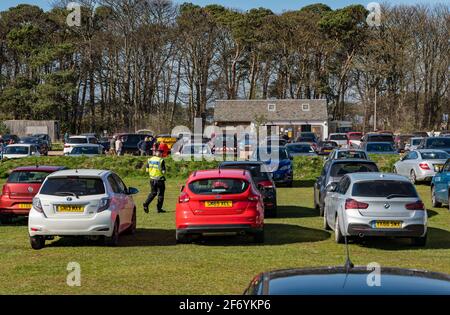 East Lothian, Schottland, Großbritannien, 3. April. 2021. UK Wetter: Sonnenschein am belebten Yellowcraig Strand. Die warme Sonne am Osterfeiertagswochenende bringt die Menschen raus, um die Natur zu genießen. Der Strandparkplatz ist an einem sonnigen Nachmittag am Osterwochenende voll mit Autos, da ein Parkwächter überprüft, ob Parkscheine gekauft wurden Stockfoto