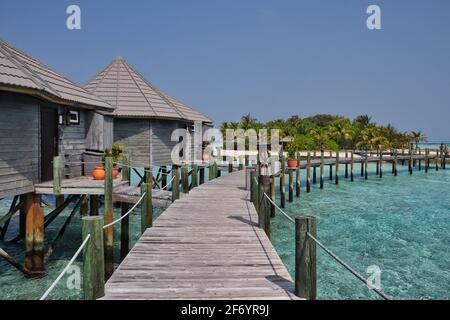Wasservilla mit Holzsteg im sonnigen Malediven. Overwater Bungalow, Turquoise Lagoon und Maldivian Island Resort. Stockfoto