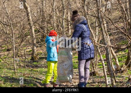 Ein Mädchen sammelt Müll im Wald, ein Mädchen hält einen großen Müllbeutel Stockfoto