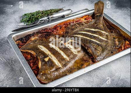 Scholle oder Flunder flacher Fisch in einer Tomatensauce in Backblech gebacken. Weißer Hintergrund. Draufsicht Stockfoto