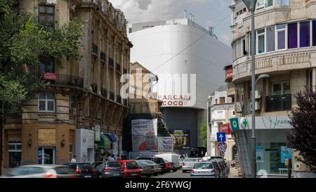 Belebte enge Straße mit modernen und modernistischen Gebäuden mit Schildern und Werbetafeln hinter Unirea Center, Bukarest, Rumänien Stockfoto