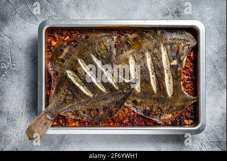 Flunder flacher Fisch in einer Tomatensauce in Backblech gebraten. Weißer Hintergrund. Draufsicht Stockfoto