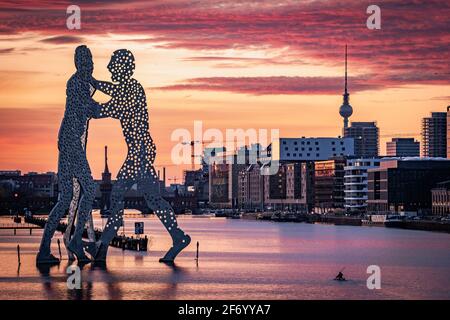 Person paddeln mit Kanu in Stree neben der Statue von Molecule man und Blick auf den berliner fernsehturm und oberbaum Brücke Stockfoto