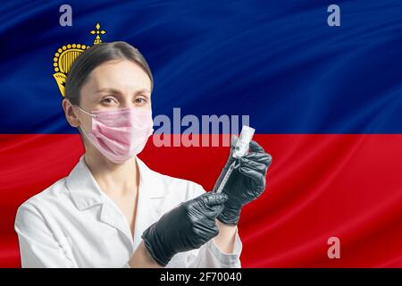 Ärztin bereitet die Impfung vor dem Hintergrund der Liechtensteiner Flagge vor. Impfkonzept Liechtenstein. Stockfoto