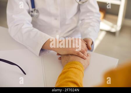 Zugeschnittenes Bild eines Arztes, der die Hand eines älteren Patienten in der Hand hält, beruhigend und Tröstet ihn Stockfoto