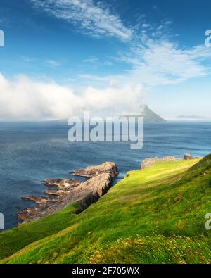 Morgenblick auf die färöische Insel Koltur mit spektakulären Wolken und blauem Wasser in einem dramatischen Tal mit Bergkette. Färöer, Dänemark. L Stockfoto