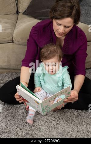 10 Monate altes Mädchen mit Mutter, vorlesen Stockfoto
