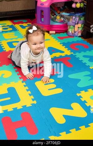 7 Monate altes Mädchen auf dem Boden, kriechend, glücklich, sich im Haar beugen Stockfoto