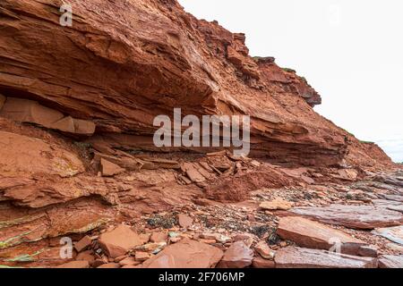 Am Cavendish Beach, auf Kanadas Prince Edward Island, ist der flache rote und türkisfarbene Sandstein mit gefallenen Steinen bedeckt, die durch Erosion verursacht wurden Stockfoto