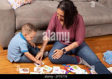3-jähriger Junge mit seiner Mutter, spielt mit Alphabet- und Zahlenkarten, die ein Puzzleteil haben, das in das Kartenlernen zu Hause passt Stockfoto