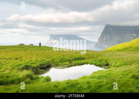 Lonely Tourist in der Nähe von kleinen See schaut auf nebligen Inseln im Atlantik von kalsoy Island, Färöer, Dänemark. Landschaftsfotografie Stockfoto