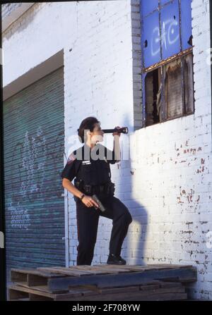 Austin, Texas, USA, 1997: Polizistin untersucht gebrochenes Fenster im Lagerhaus. ©Bob Daemmrich Stockfoto