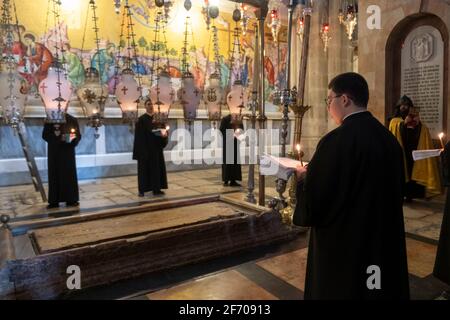 Mitglieder der armenisch-apostolischen Kirche singen während der Feier des Karsamstags in der Grabeskirche am 03. April 2021 in Jerusalem, Israel, Vesper um den Stein der Salbung oder den Stein der Unktion. Die Christen in Israel markieren in diesem Jahr die Karwoche, inmitten von Anzeichen, dass sich die Krise des Coronavirus abnimmt und religiöse Stätten nur einer begrenzten Anzahl von Gläubigen zugänglich sind. Stockfoto