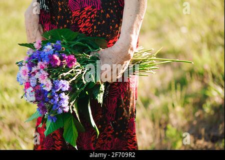 80-jährige Frau mit einem Blumenstrauß in der Hand. Stockfoto