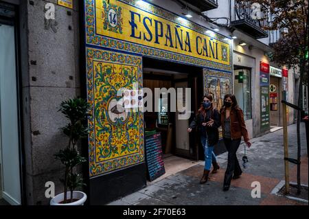 Madrid, Spanien. April 2021. Zwei Frauen, die Gesichtsmasken tragen, um die Ausbreitung des Coronavirus zu stoppen, gehen an einer typischen spanischen Taverne im Zentrum von Madrid vorbei. Die Polizei kontrolliert den Zustrom von Menschen in der Innenstadt von Madrid als sanitäre Maßnahme, um Coronavirus-Infektionen während der Osterferien zu verhindern. Quelle: Marcos del Mazo/Alamy Live News Stockfoto