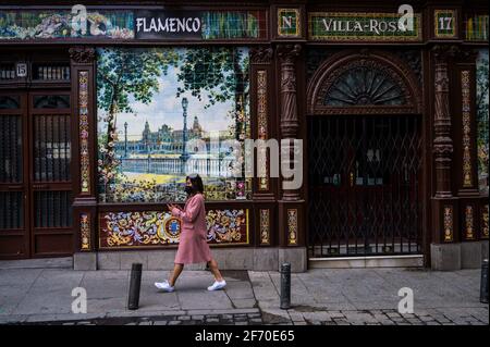 Madrid, Spanien. April 2021. Eine Frau, die Gesichtsmasken trägt, um die Ausbreitung des Coronavirus zu stoppen, geht an einer geschlossenen Flamenco-Taverne in der Innenstadt von Madrid vorbei. Die Polizei kontrolliert den Zustrom von Menschen in der Innenstadt von Madrid als sanitäre Maßnahme, um Coronavirus-Infektionen während der Osterferien zu verhindern. Quelle: Marcos del Mazo/Alamy Live News Stockfoto