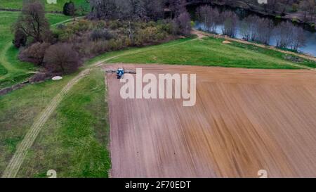 Luftaufnahme eines Traktors, der ein landwirtschaftliches Feld in einem ländlichen Teil von Suffolk, Großbritannien, pflügt Stockfoto