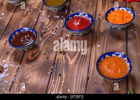 Sauce im Sortiment auf braunem Holzboden, verziert mit Pfeffer, Kirschtomaten, Gewürzen, grobem Salz. Speisekarte im Restaurant. Stockfoto